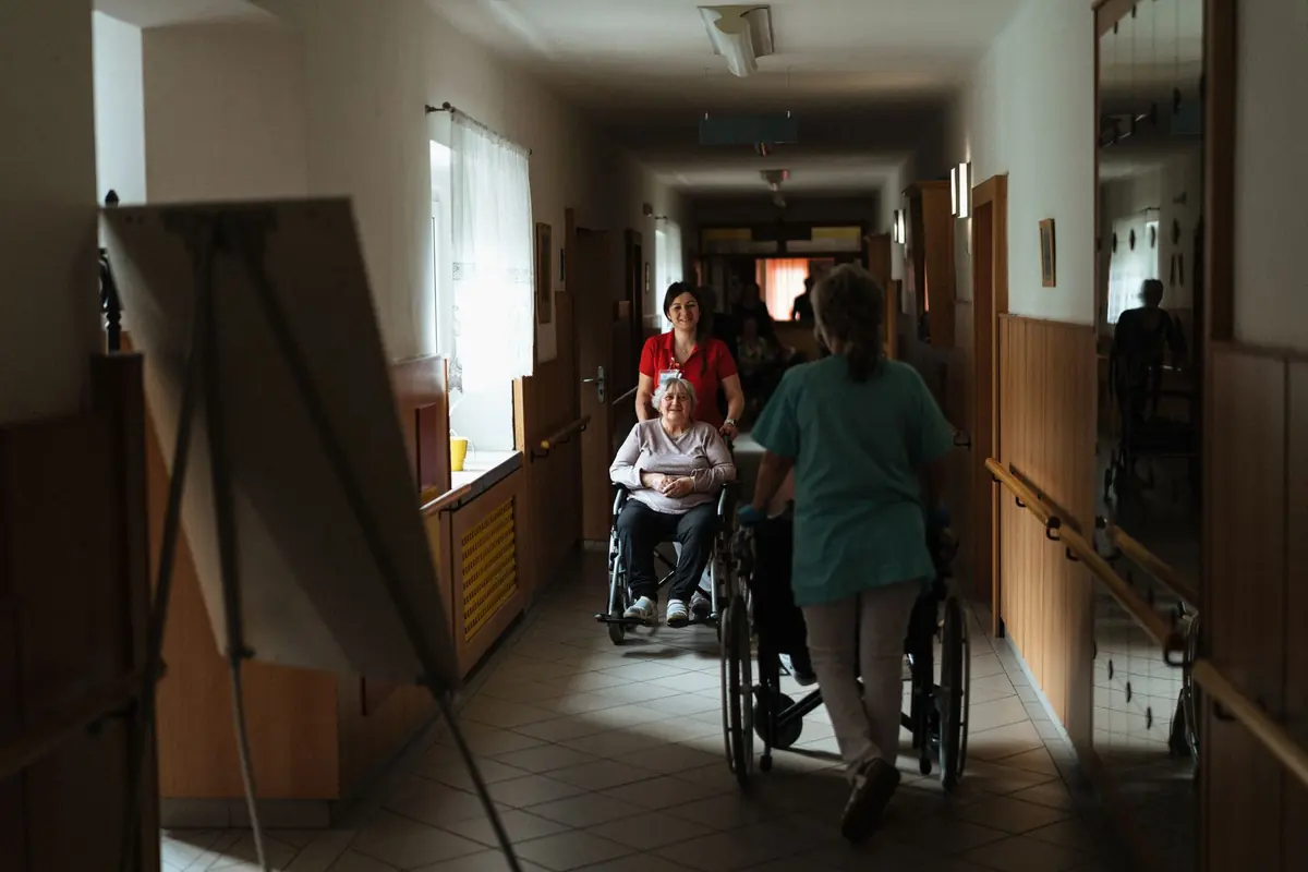 Résidents accompagnés dans le couloir d'une maison de retraite